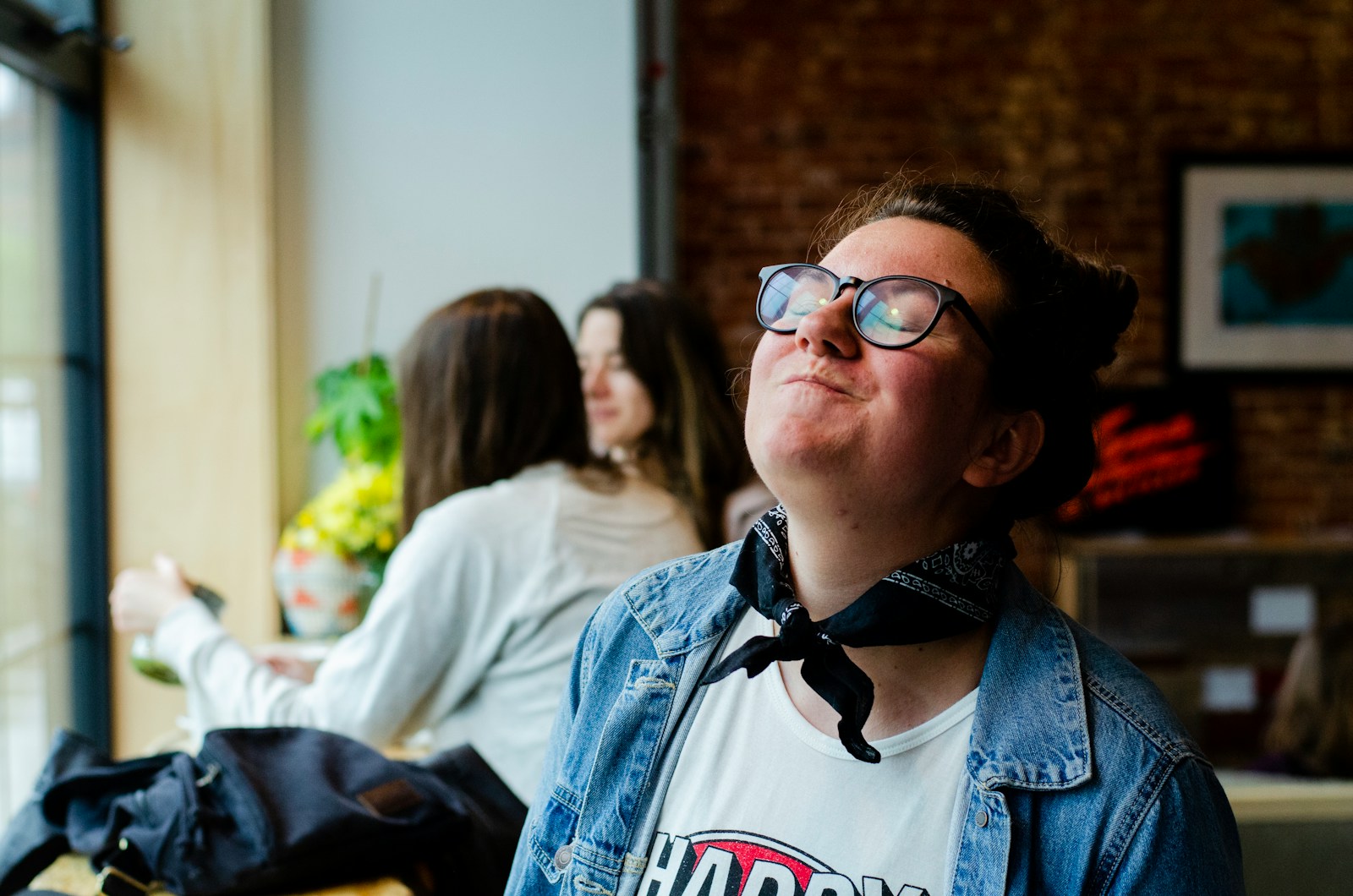 woman wearing blue denim jacket sitting and smiling while closing her eyes