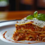 a white plate topped with lasagna covered in sauce